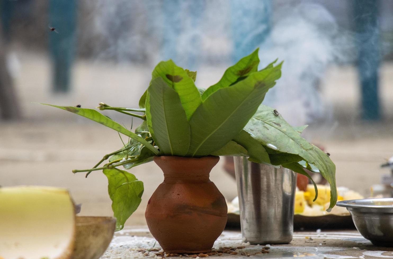 Traditional Hindu wedding and worship rituals photo with a clay water pot and green leaves in it. Hindu puja and prayer elements. Close-up photo of a clay water pot and a glass. Hindu wedding concept.