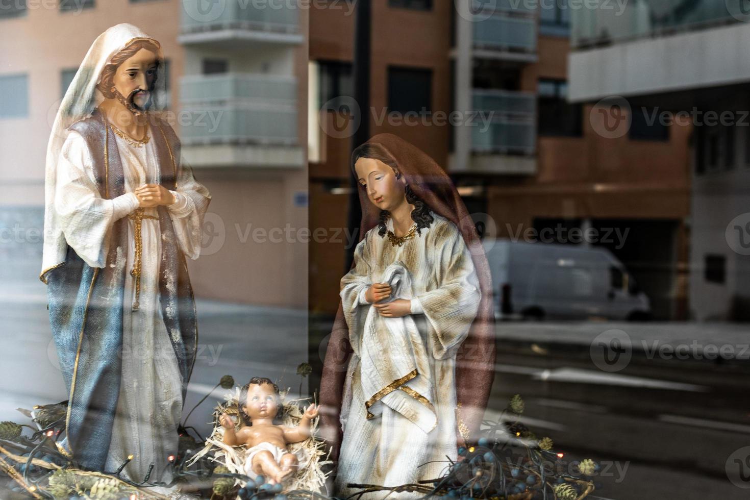 large figures of saints from the nativity scene for Christmas, close to the reflection of the city in the glass photo