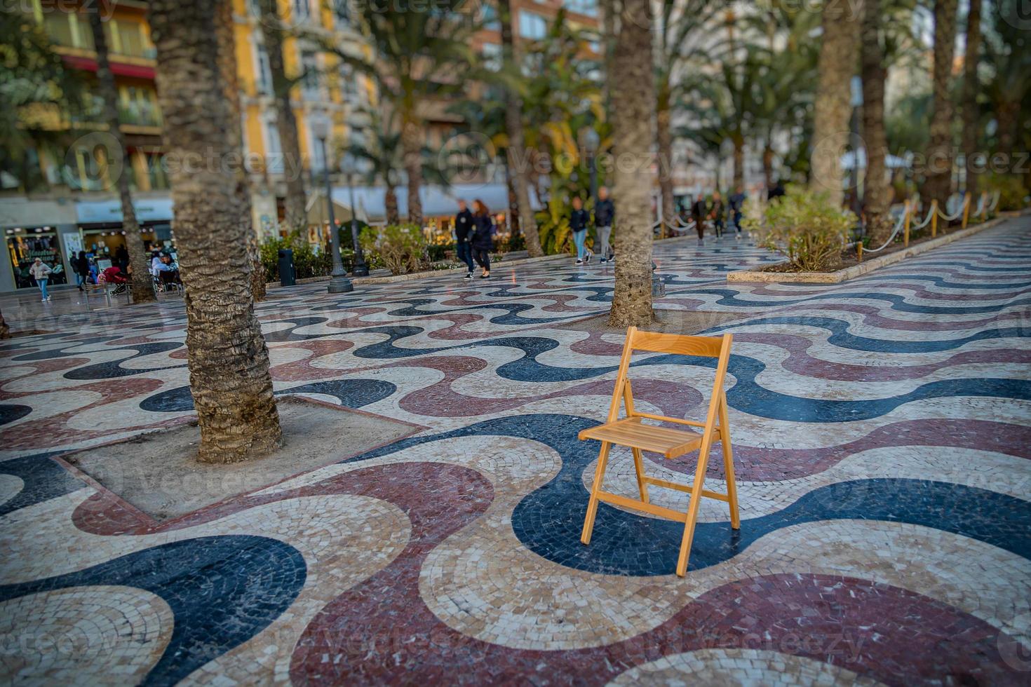 Explanada promenade in Alicante Spain landmark with wooden empty chair on mosaic photo