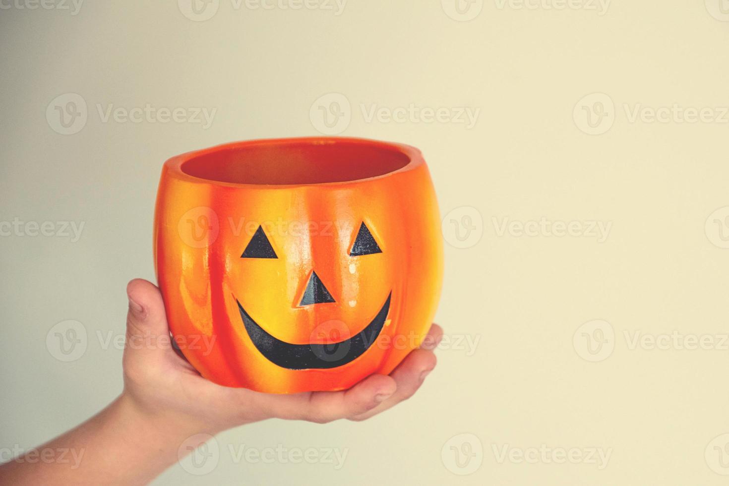 beautiful  orange flower pot pumpkin for halloween on a light background held in a child's hand photo