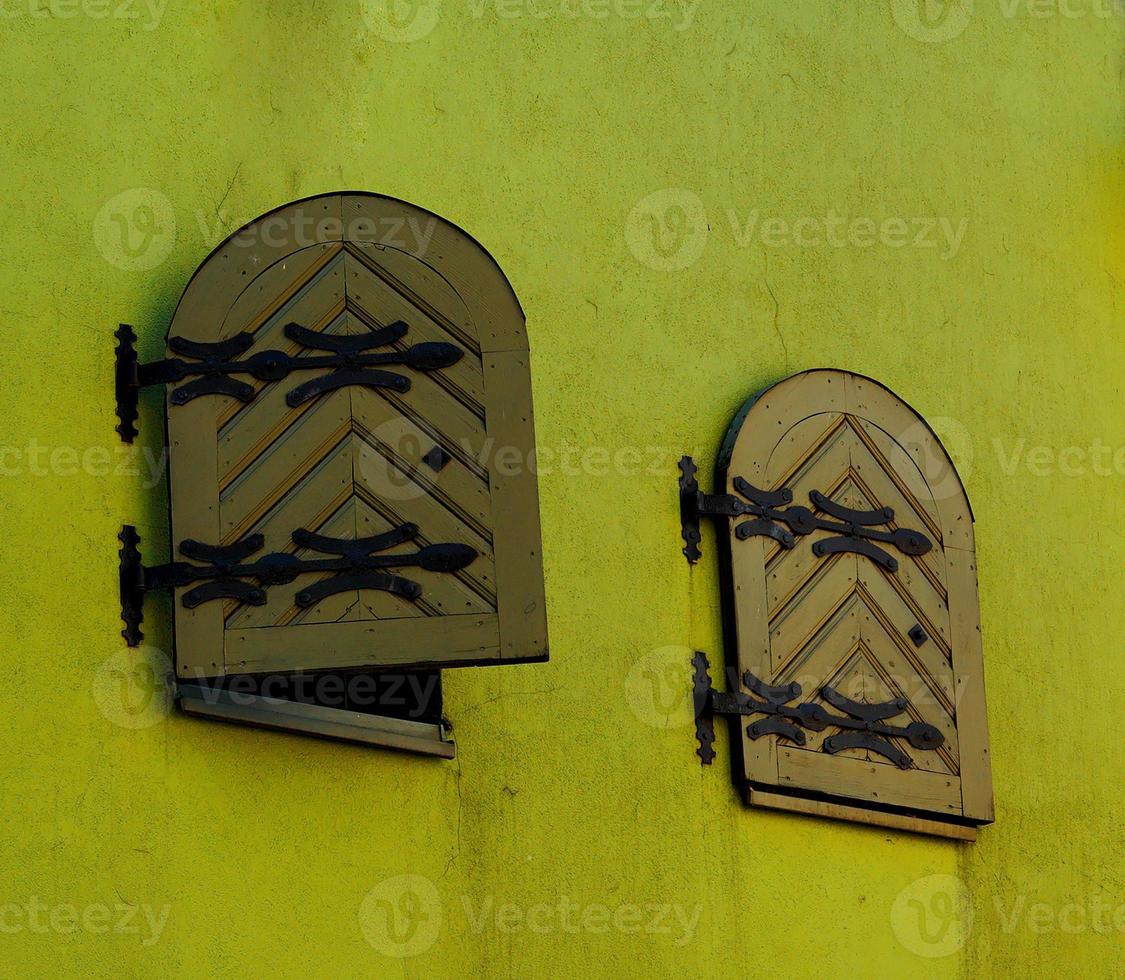 two windows with closed wooden shutters in an old historic building photo