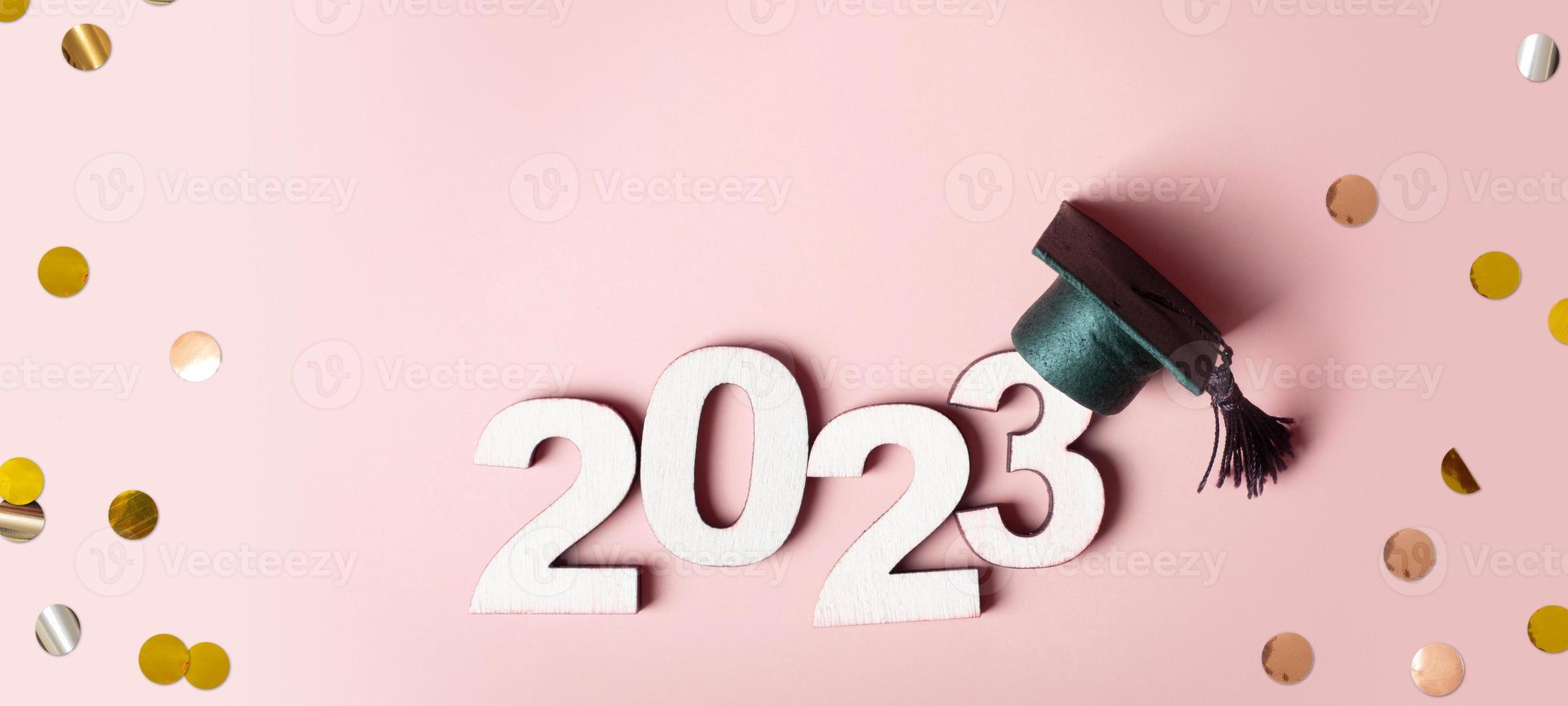 Class of 2023 concept. Wooden number 2023 with graduated cap on colored background photo