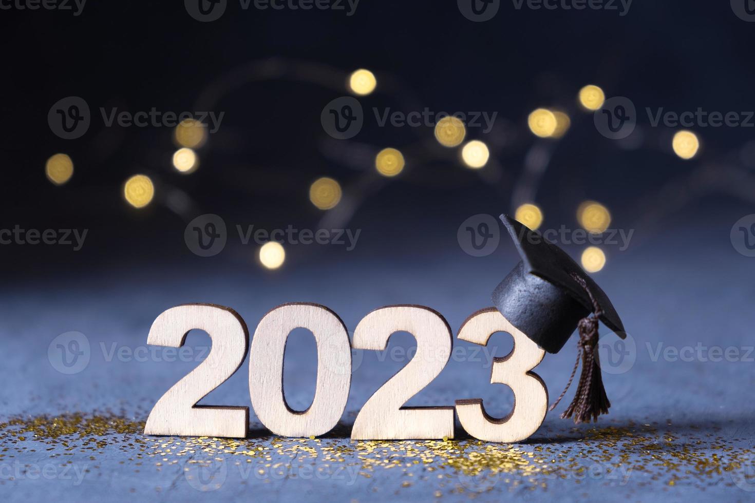 Class of 2023 concept. Wooden number 2023 with graduate hat on dark background with bokeh photo