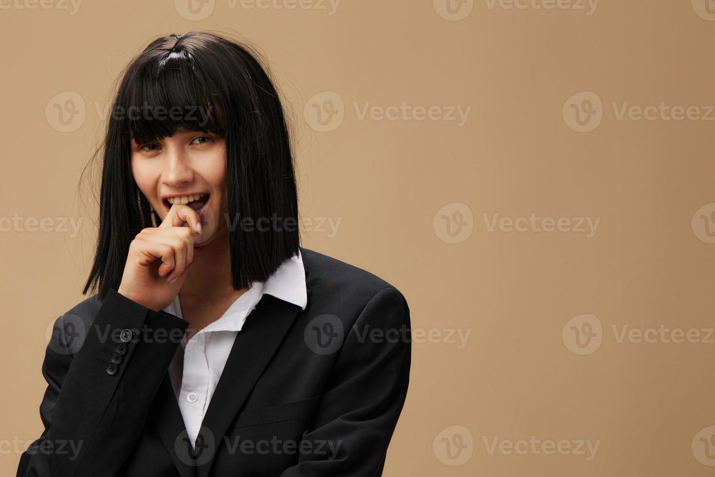 Pensive happy smiling pretty brunet lady in classic suit bites finger look at camera posing isolated on pastel beige studio background. Copy space Banner Offer. Pulp Fiction concept. Fashion Cinema photo