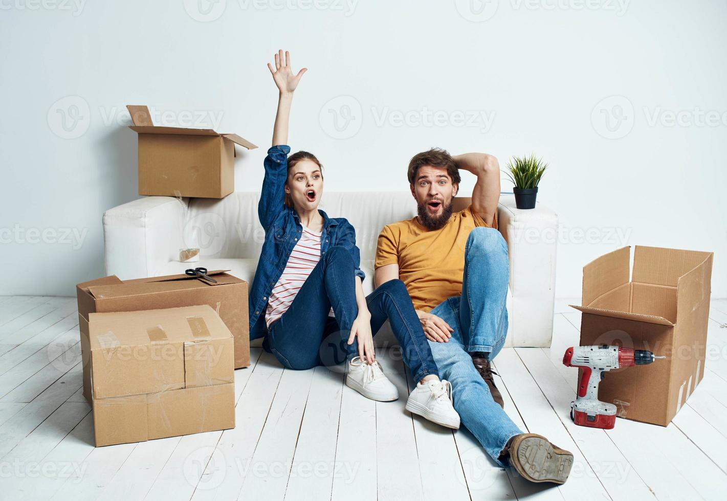 A man and a woman are sitting on the floor with open boxes and tools for repair photo