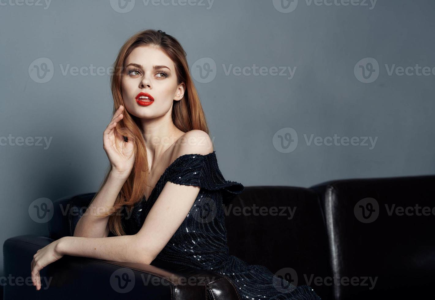 Charming Woman in Black Dress on a Leather Sofa Bright Makeup Model photo
