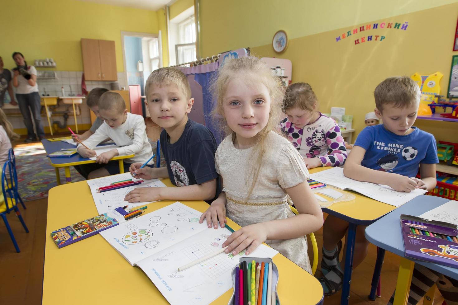 Belarus, the city of Gomel, April 25, 2019. Open day in kindergarten.Children in a drawing lesson in kindergarten. Preschoolers with pencils and coloring are sitting at the tables. photo