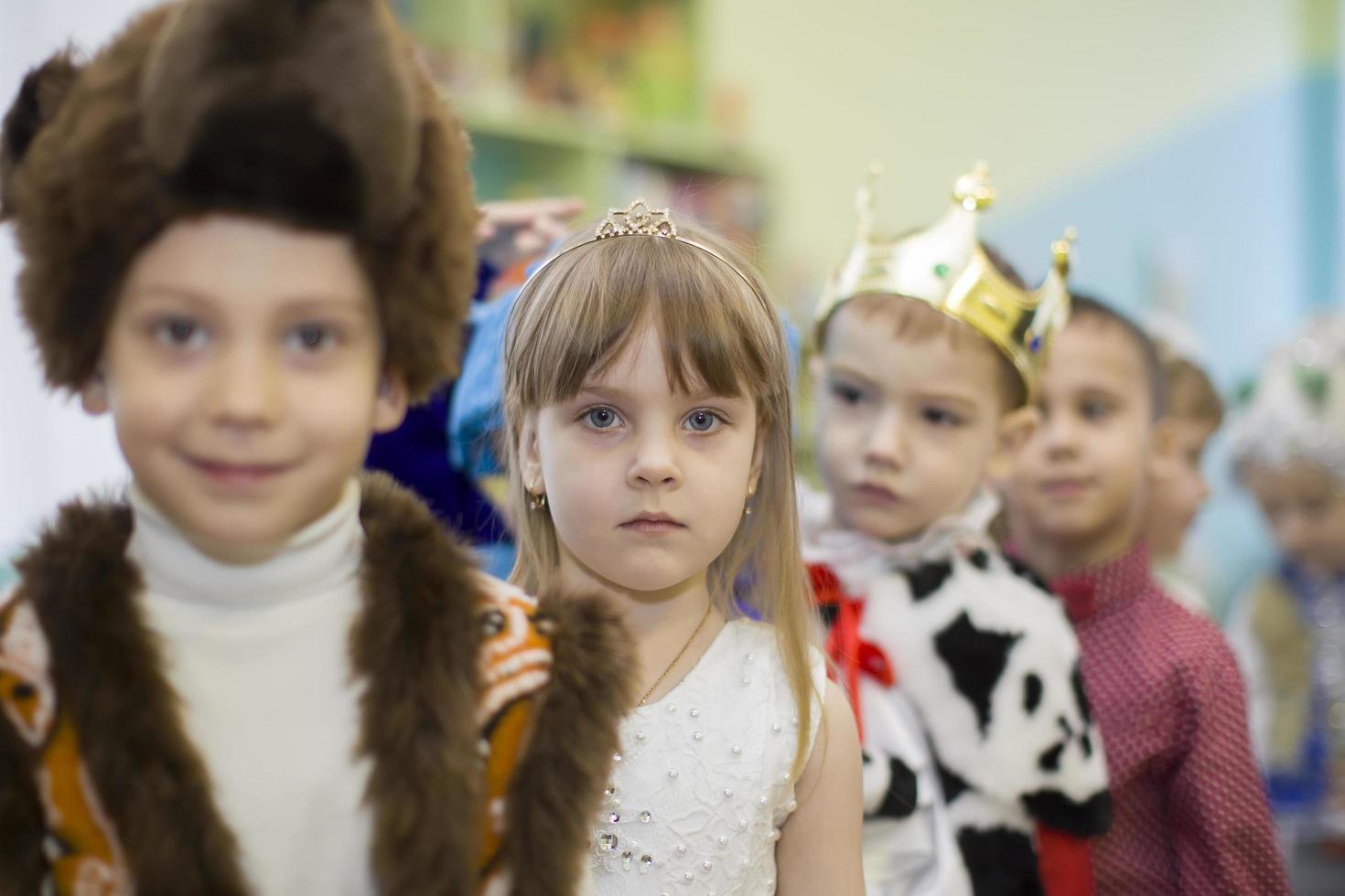 niños desde jardín de infancia Vamos a el Navidad fiesta. pequeño Niños y muchachas en carnaval disfraces foto