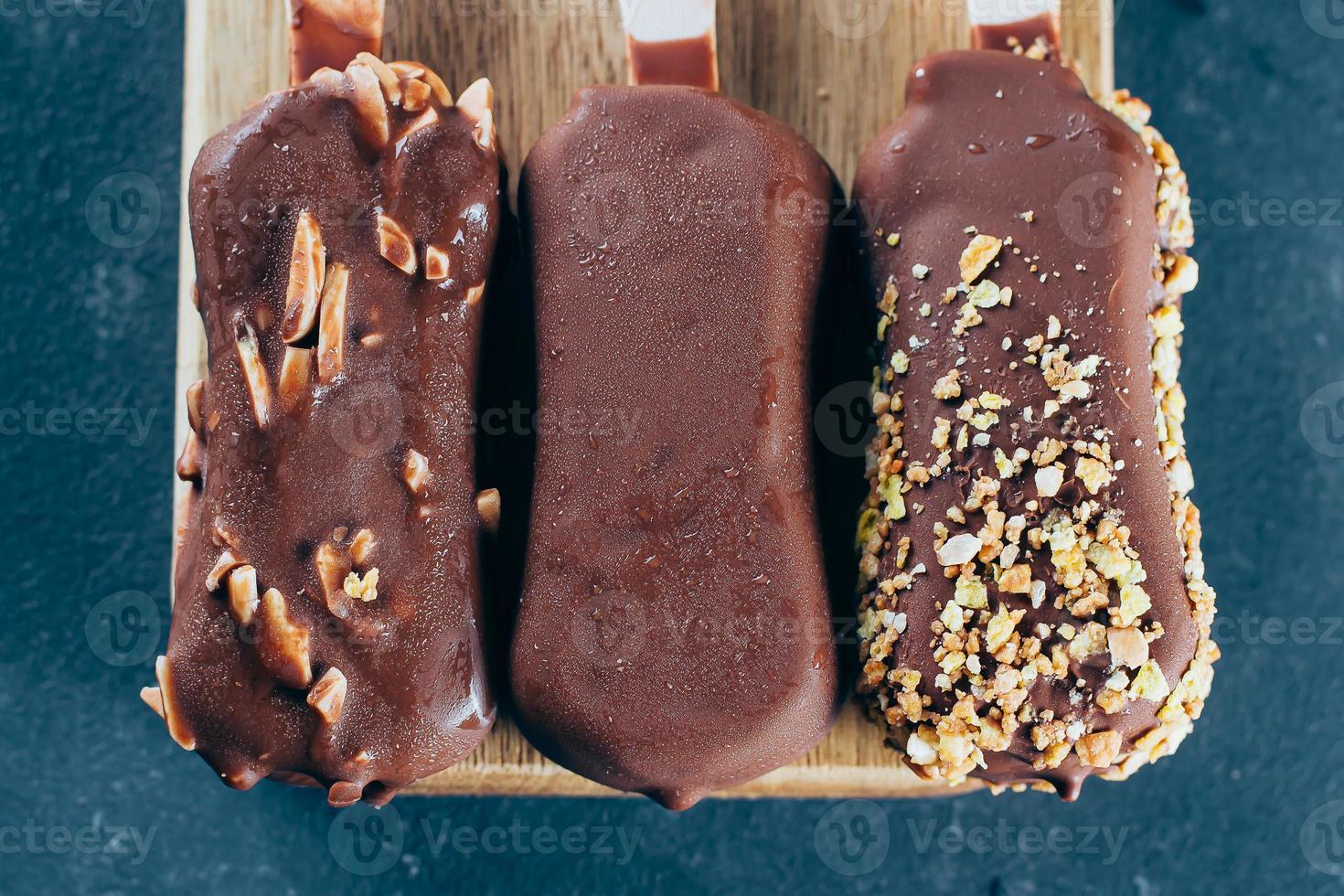 Eskimo ice cream on stick in chocolate glaze on blue background. Yummy sweet food snack treat photo