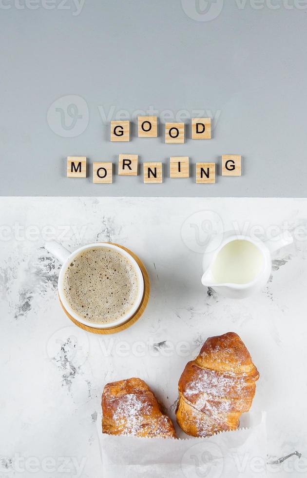 Good Morning Breakfast Minimal Concept. Cup of coffee, croissant and text Good Morning. Flat lay photo