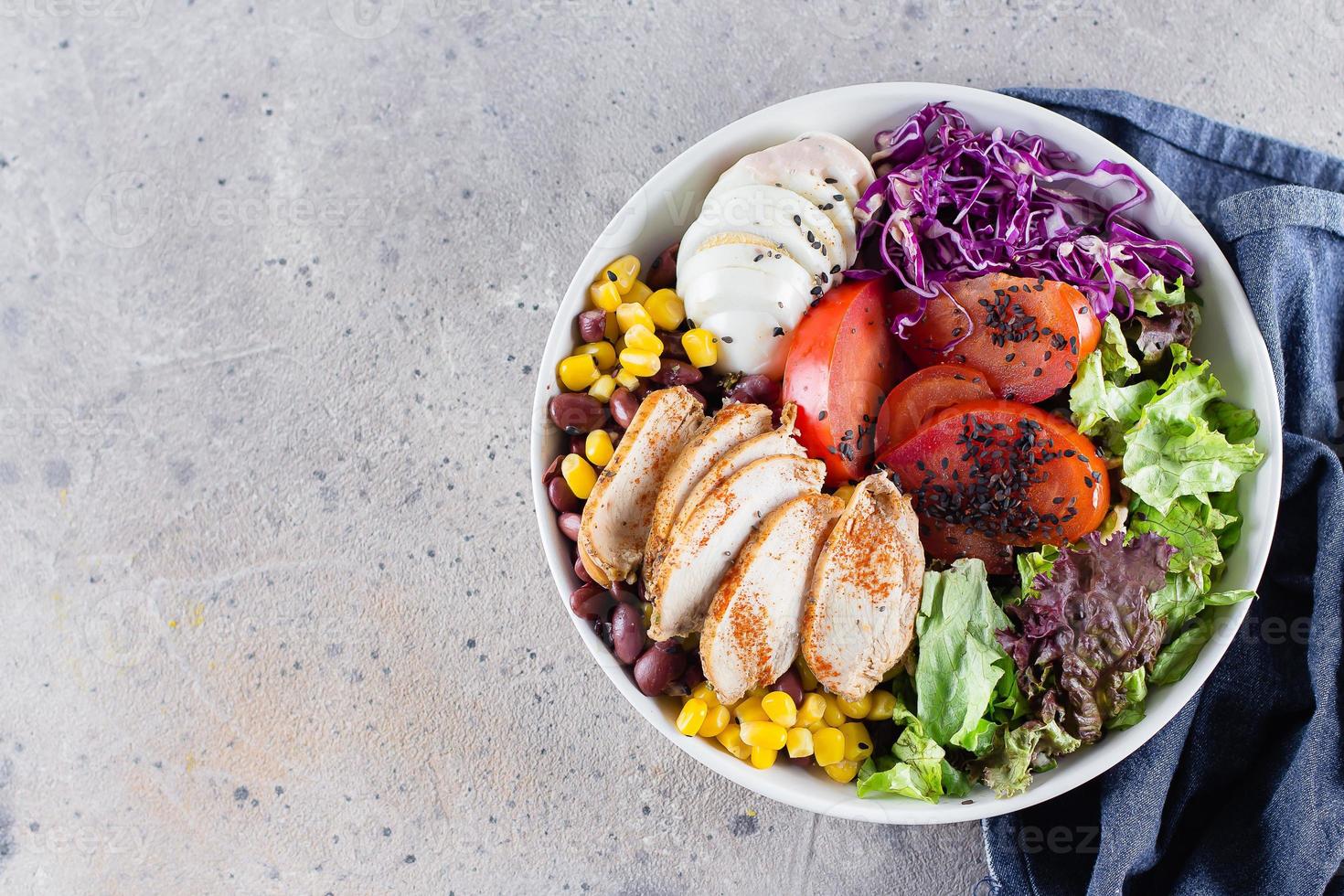 Healthy lunch salad with chicken, egg, tomatoes, lettuce, red beans, red cabbage, sauce, top view photo