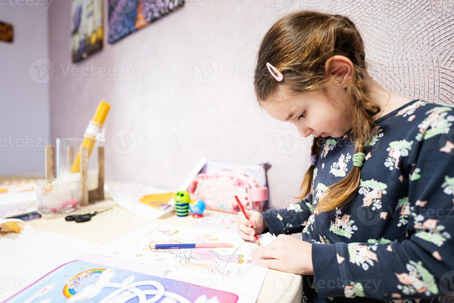 Little girl painting by pencil at home. photo