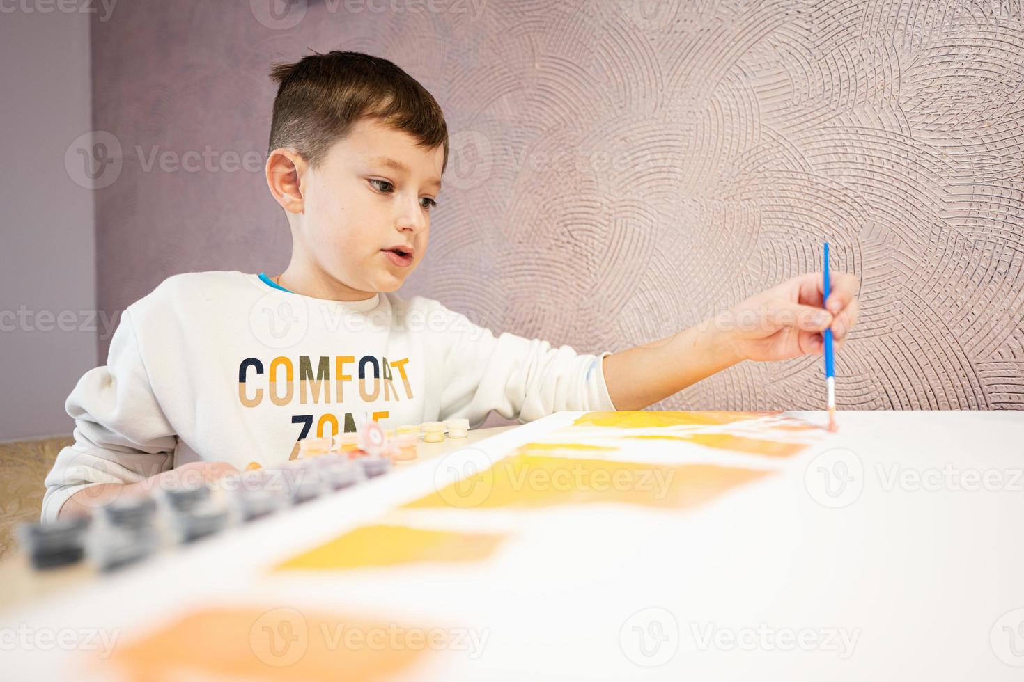 Left handed boy is painting by numbers with gouache at home. Comfort zone. photo
