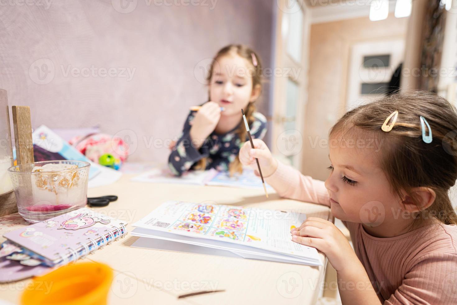 Two cute little sisters painting at home. photo