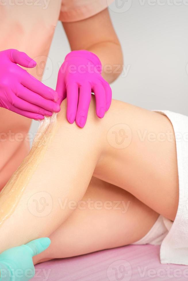 Beautician epilating leg of female photo