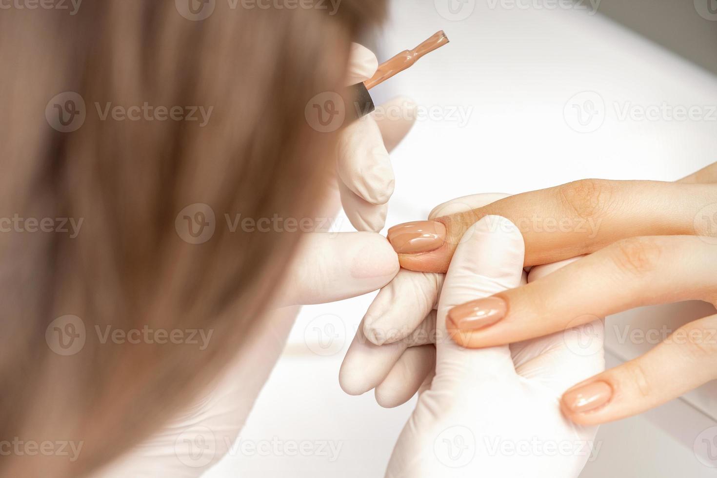 Manicurist applying beige nail polish photo