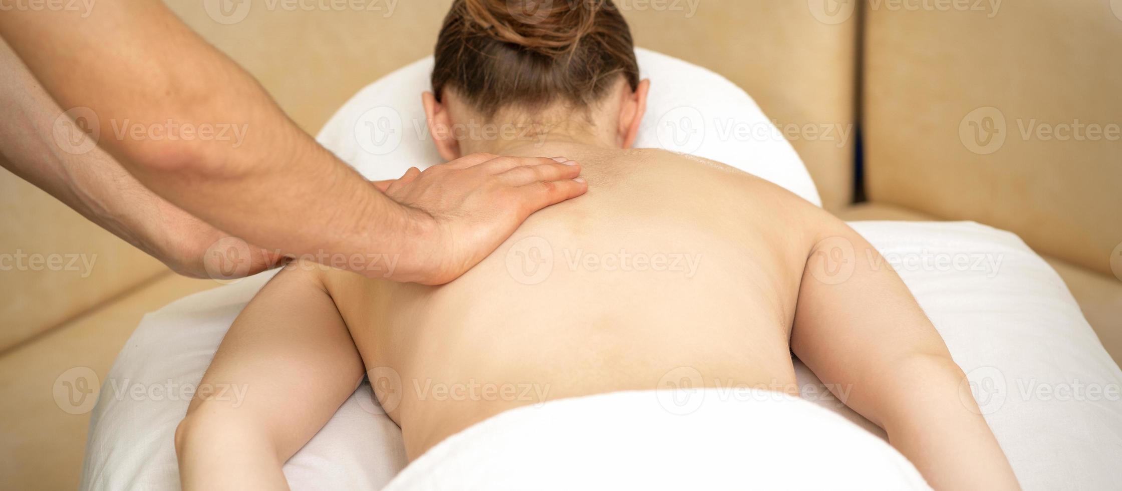 Masseur massaging back of woman photo