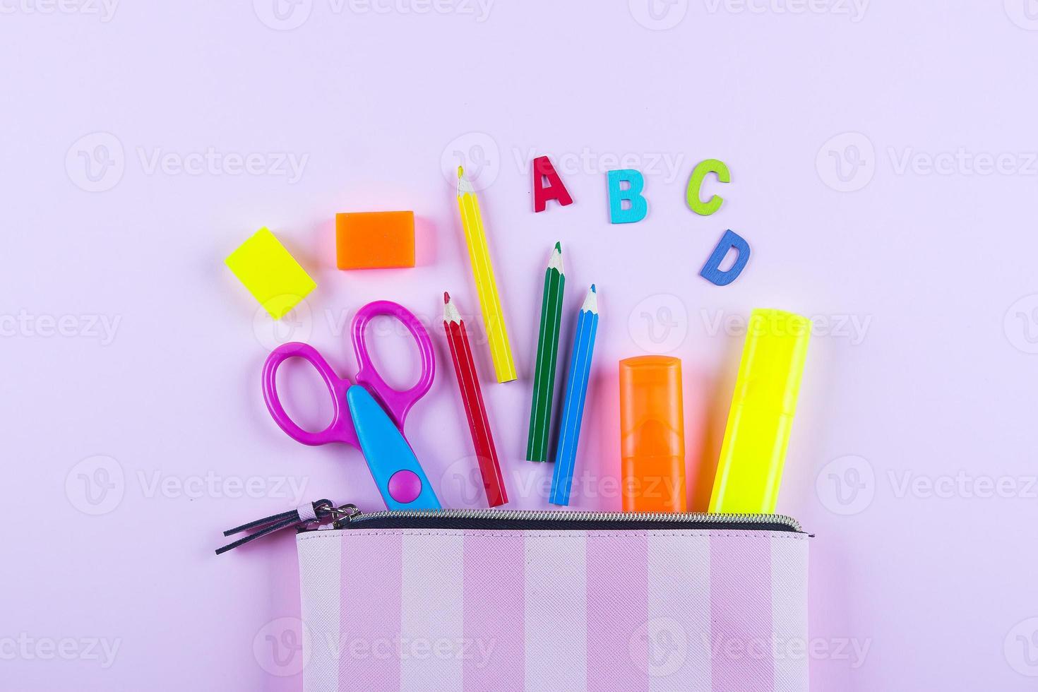 Back to school concept. School supplies in pencil case. Pink background with copy space. Flat lay photo