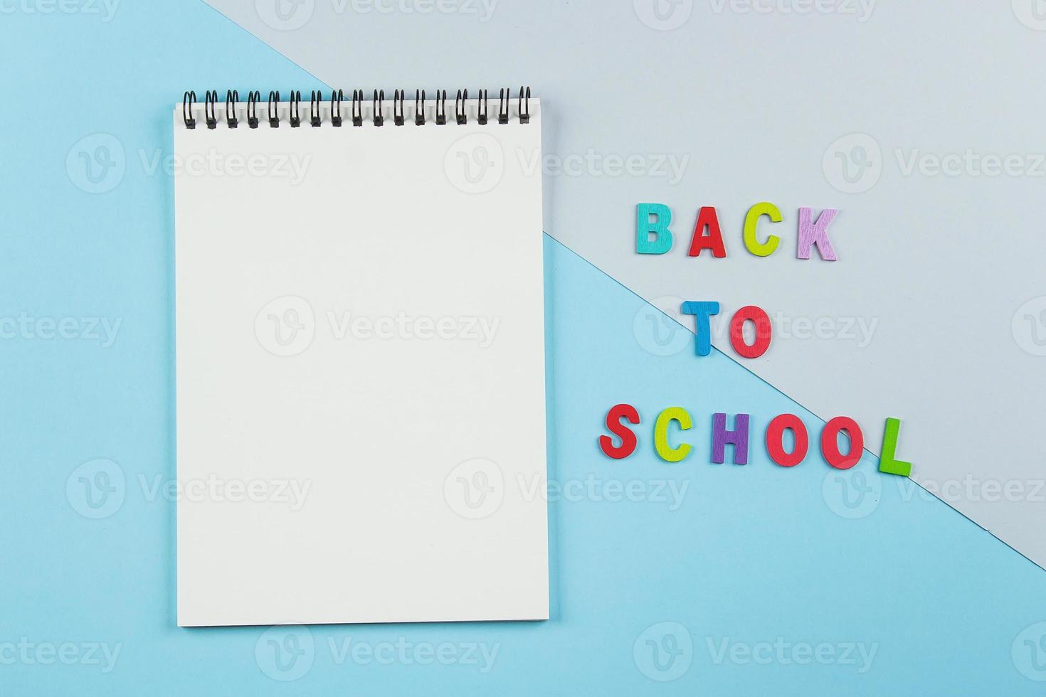 Top view of empty notebook, inscription by letters back to school on pastel background. photo