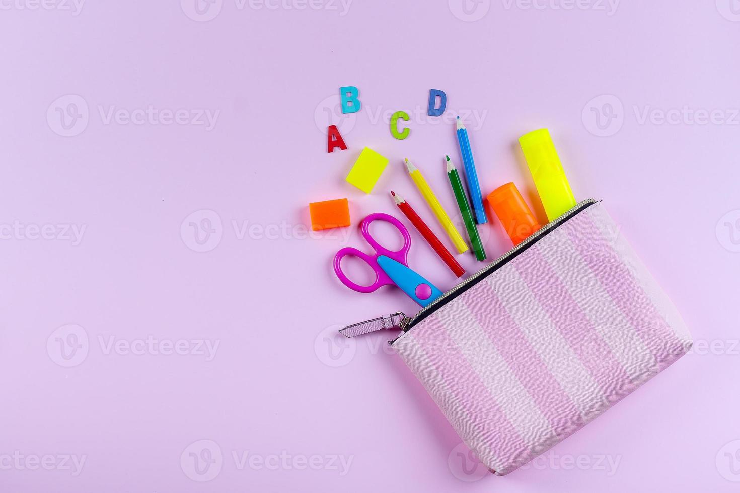 Back to school concept. School supplies in pencil case. Pink background with copy space. Flat lay photo