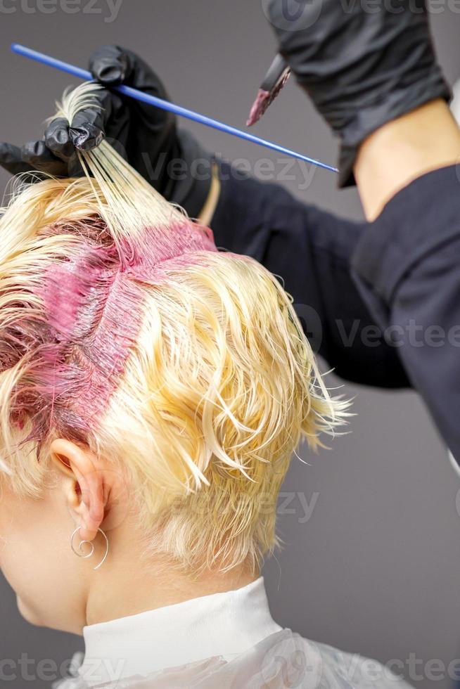 Hairdresser's hands applying pink dye photo