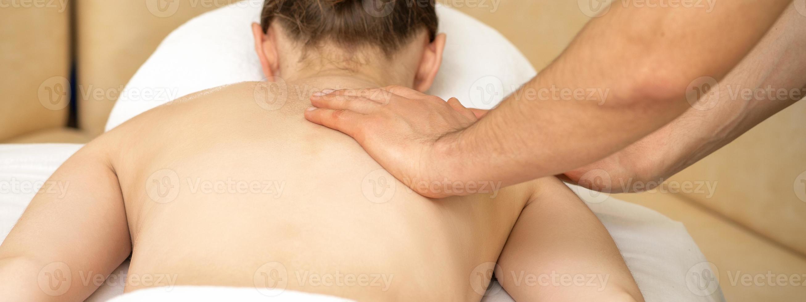 Masseur massaging back of woman photo