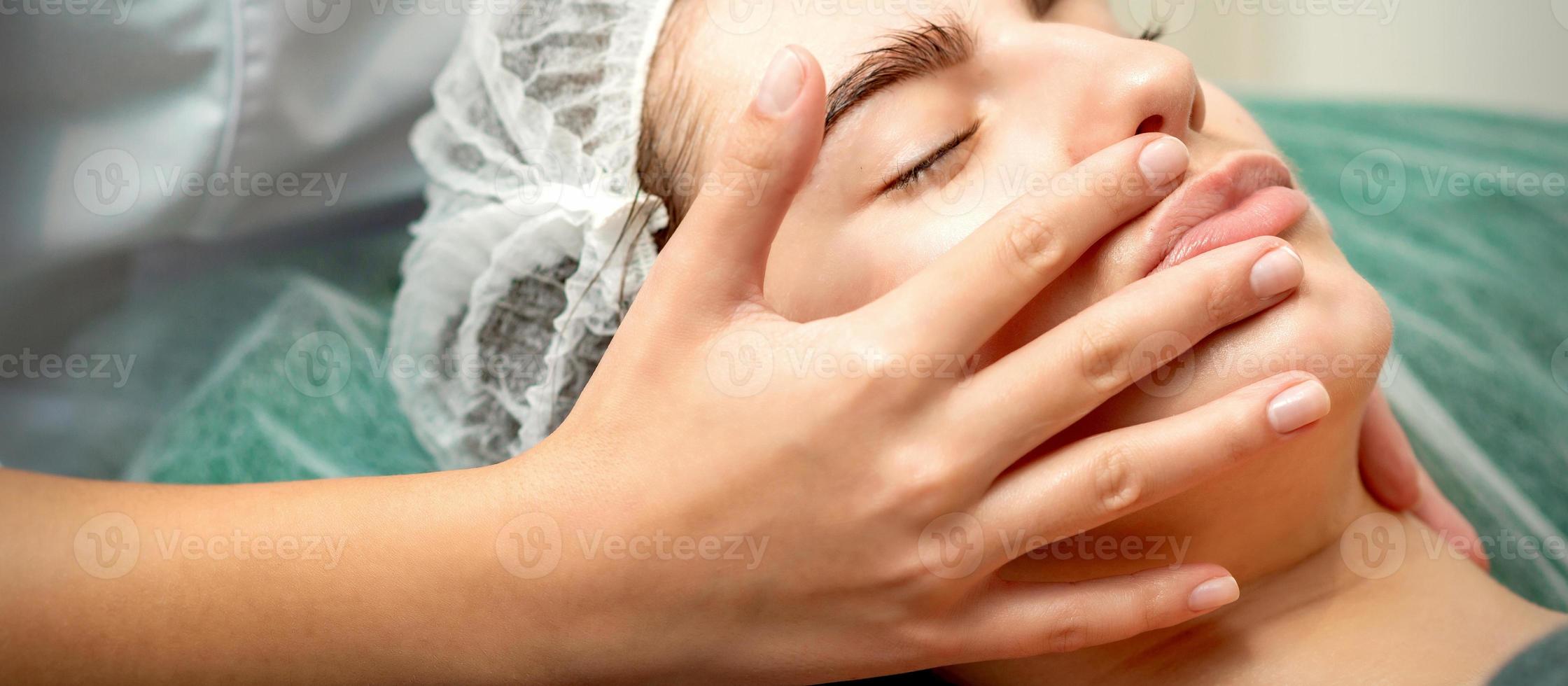 Young woman receiving facial massage photo