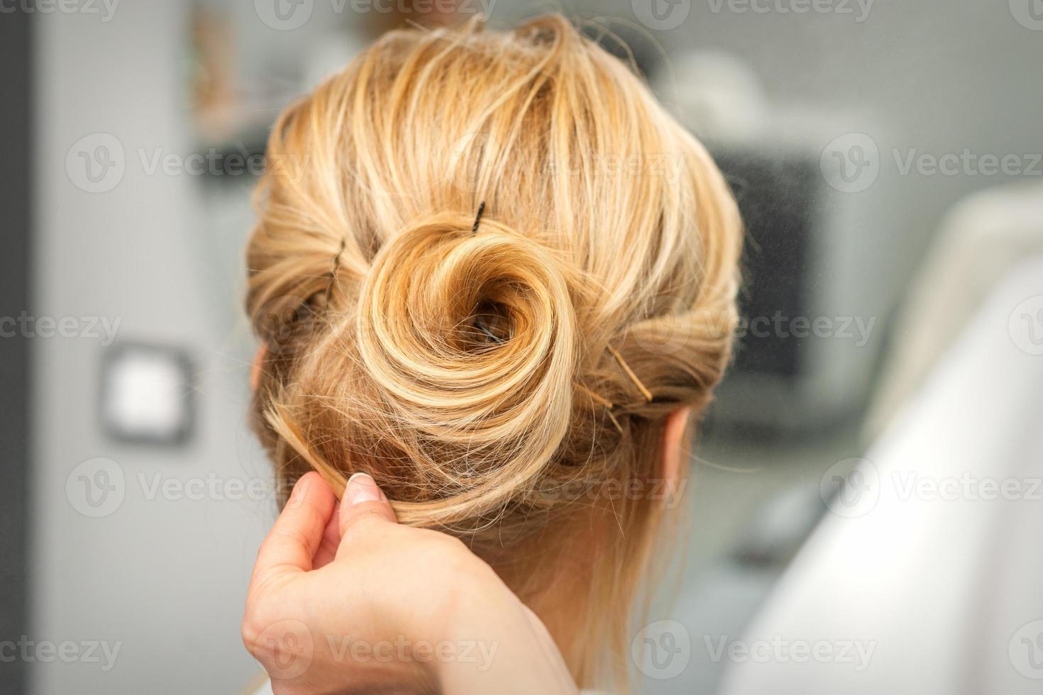 Female hairdresser styling blonde hair photo