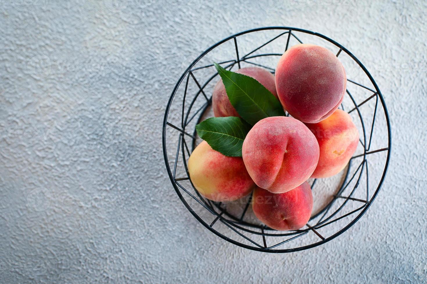 Fresh peaches. Peaches in metal basket on light concrete background. Flat lay, top view, copy space. photo