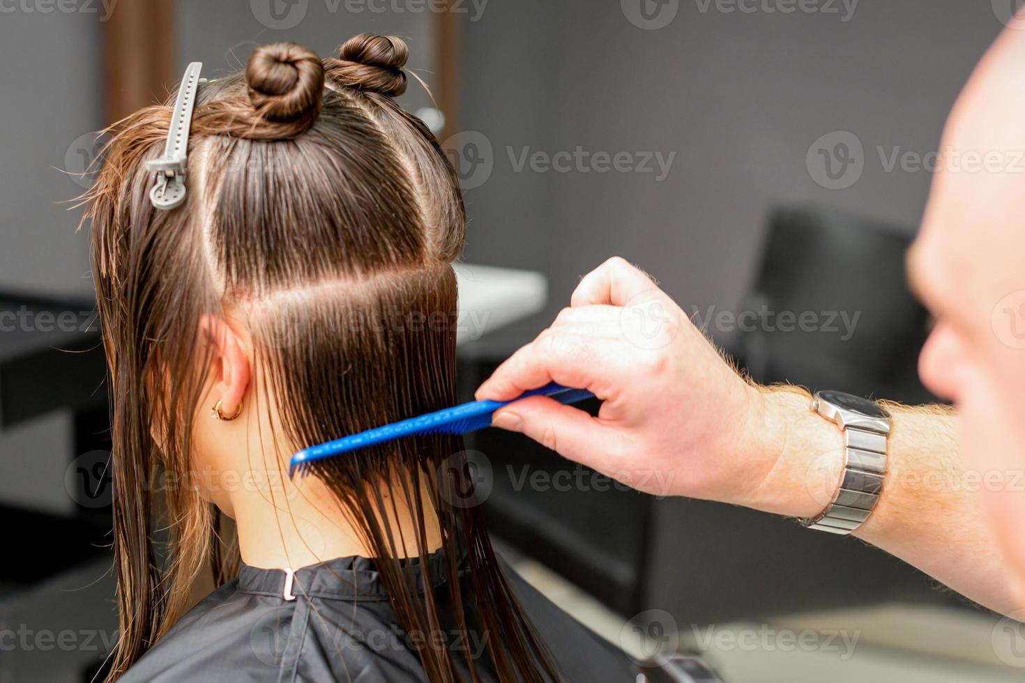 Hairdresser combing female wet hair photo