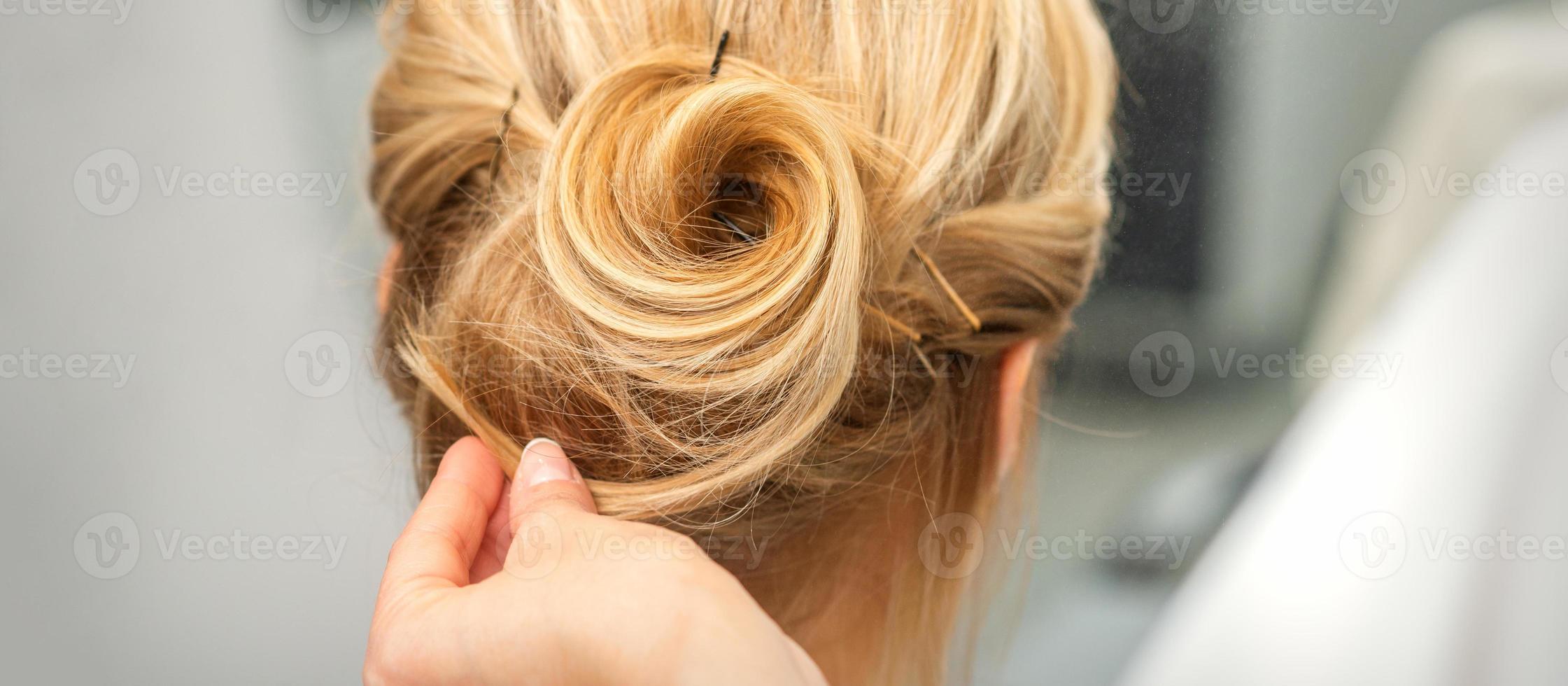 Female hairdresser styling blonde hair photo