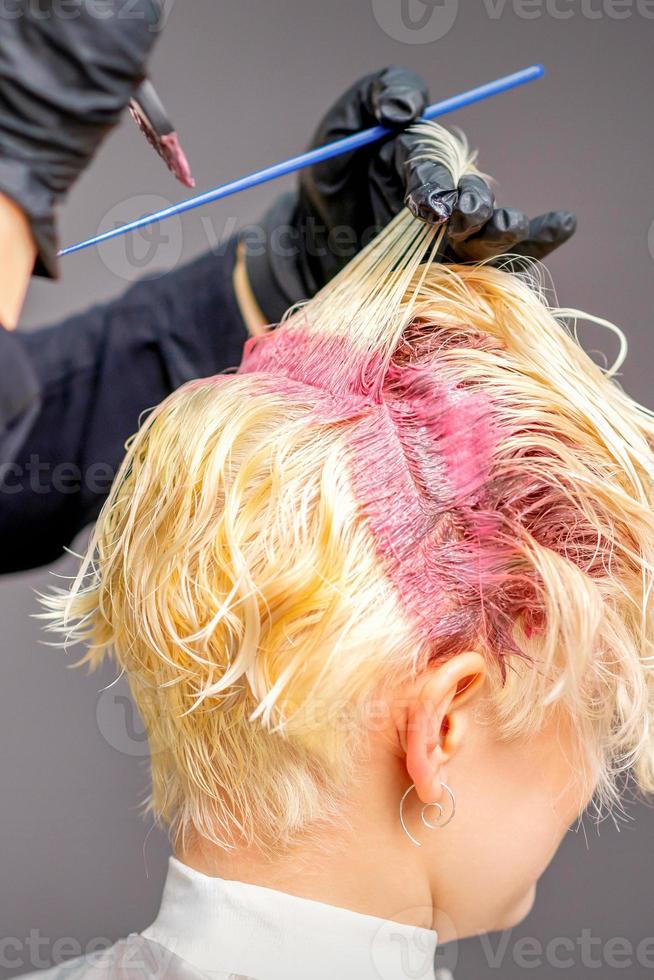 Hairdresser's hands applying pink dye photo