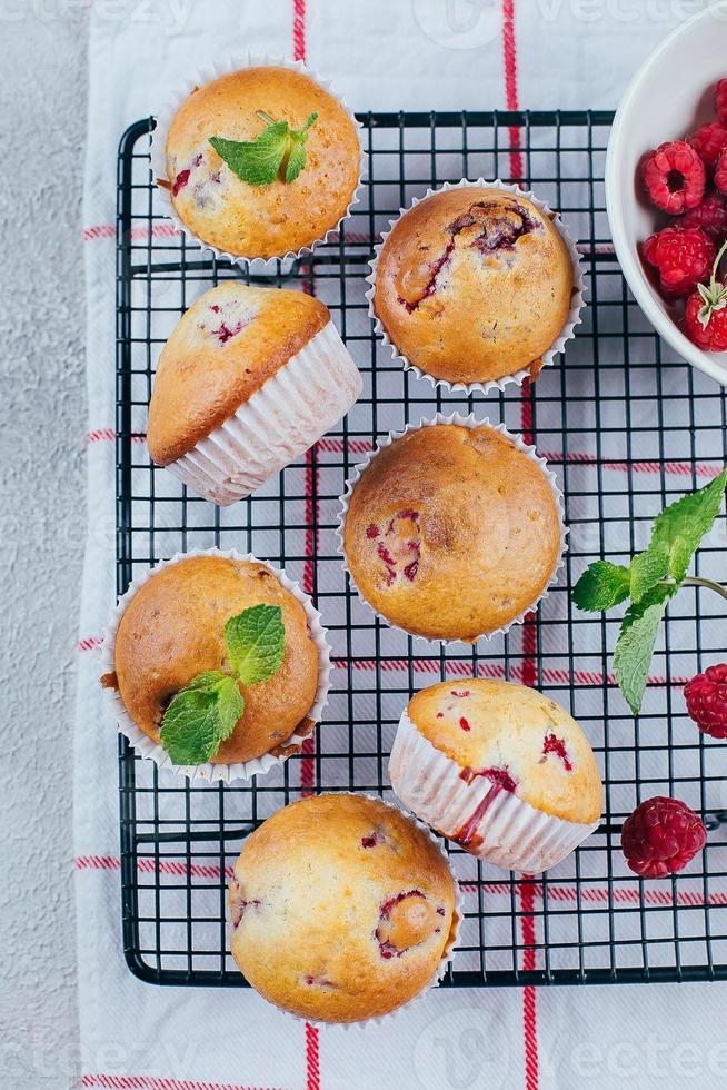 Berry raspberry muffins on metal grill for cooling on light concrete background. Top view. photo