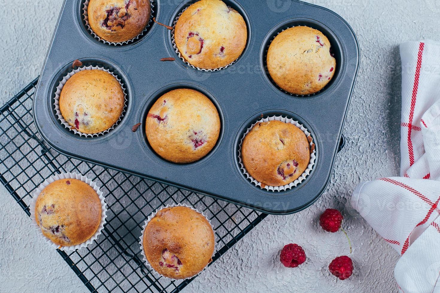 Baked Raspberry Muffins on a cooling rack on blue concrete table background. Breakfast concept photo