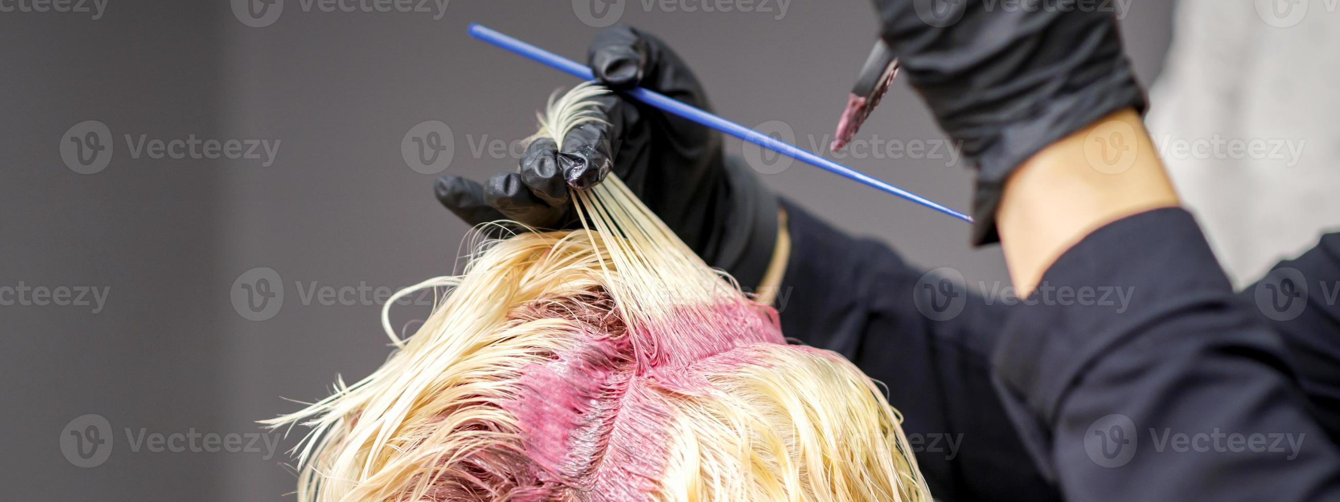 Hairdresser's hands applying pink dye photo
