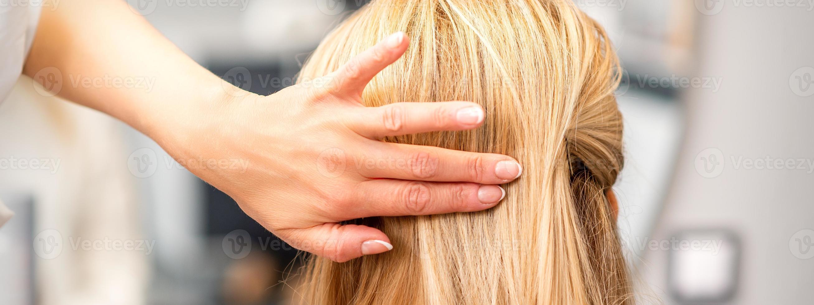 Female hairdresser styling blonde hair photo