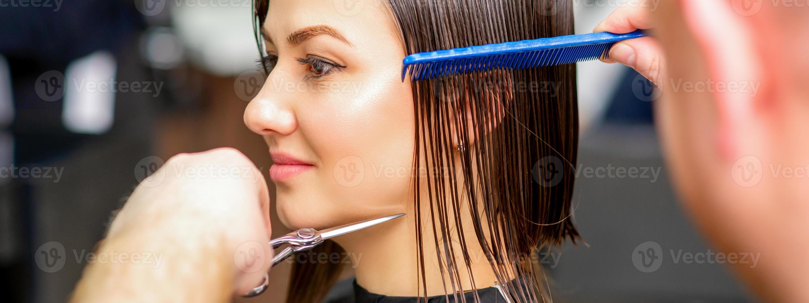 Hairdresser cuts wet hair of woman photo