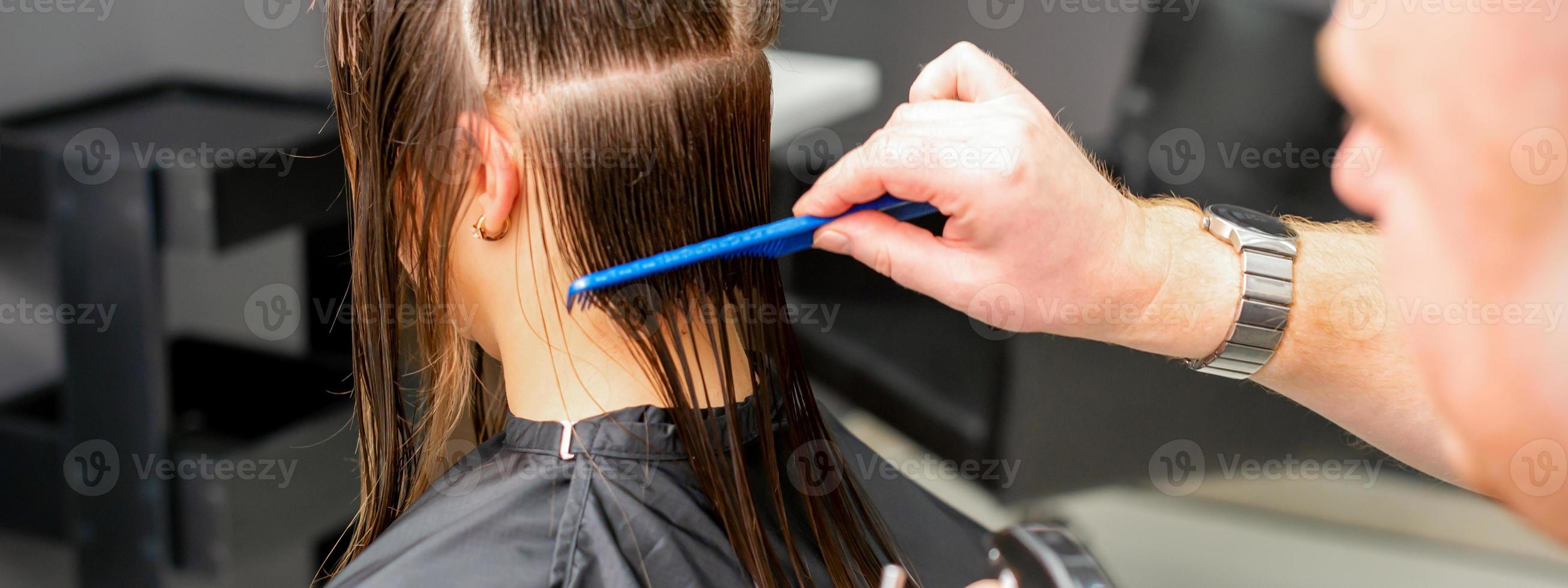 Hairdresser combing female wet hair photo