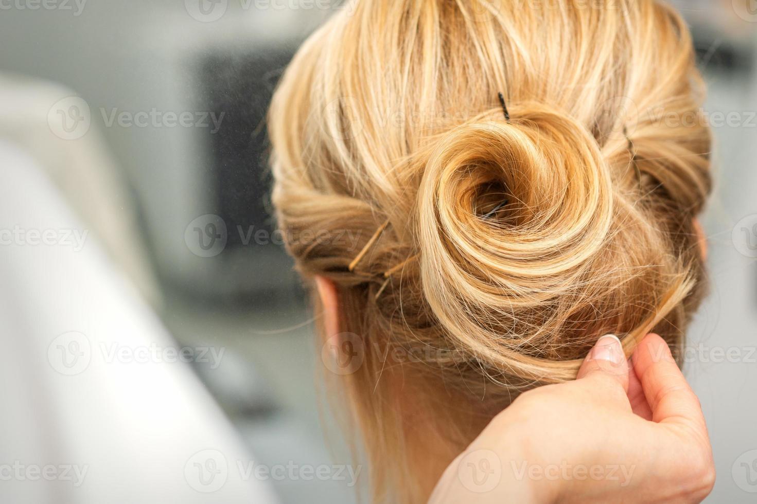 Female hairdresser styling blonde hair photo