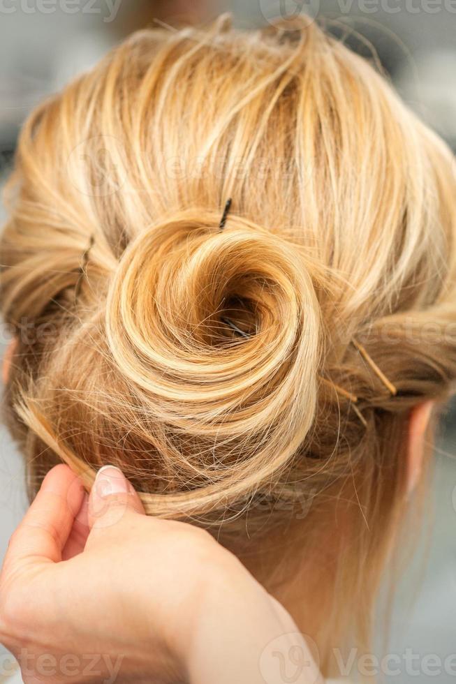 Female hairdresser styling blonde hair photo