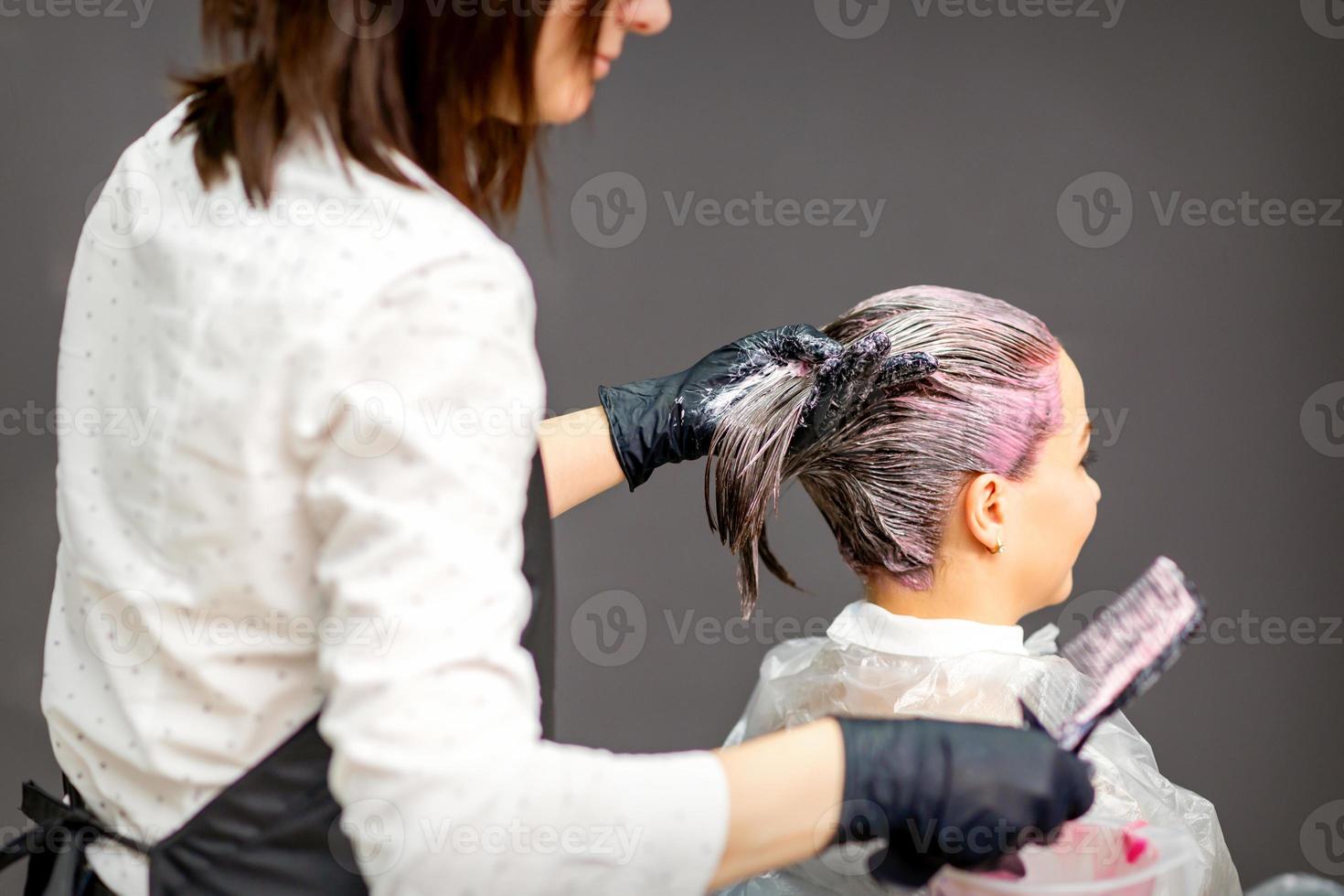 Hairdressers dyeing hair of woman photo