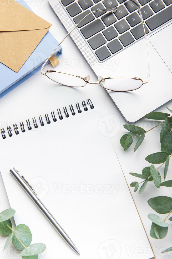 Modern white office desk table with laptop, notebook and other supplies. photo