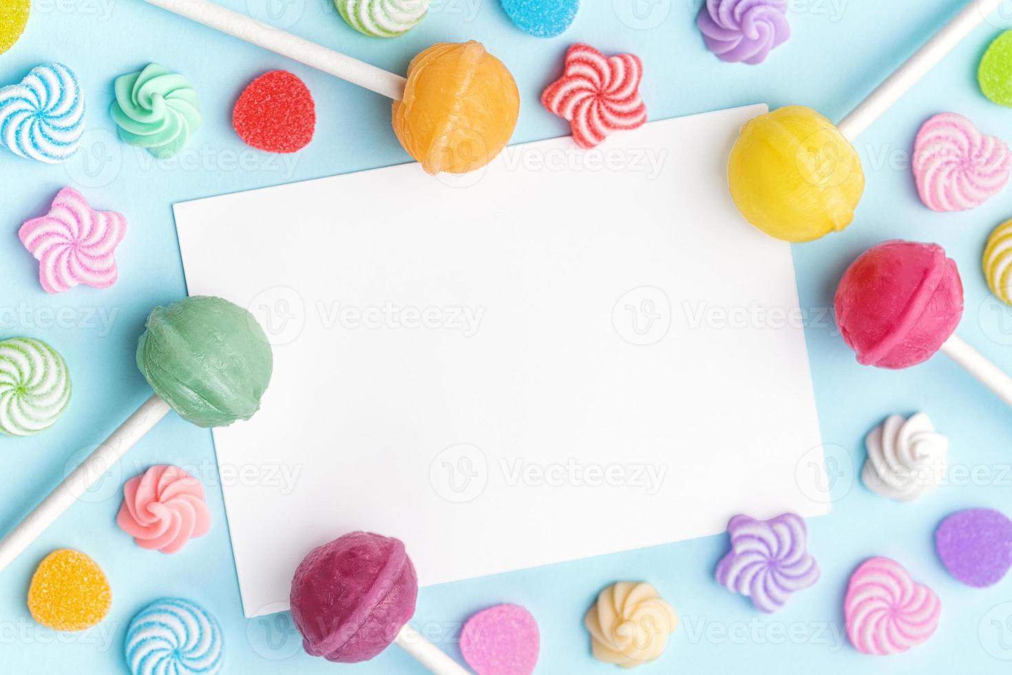 Sweet lollipops and candies and blank greeting card on blue background photo