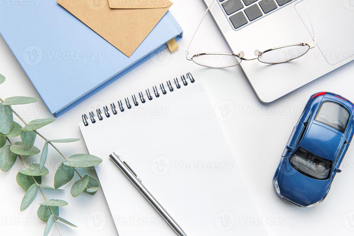 Modern white office desk table with laptop, notebook, toy car and other supplies. photo