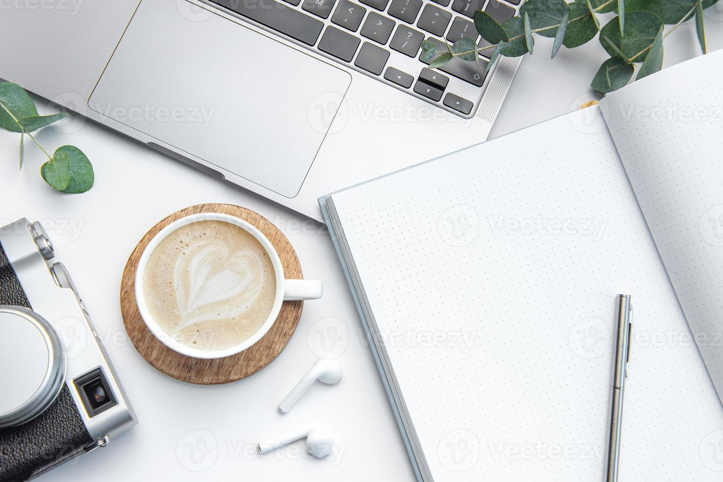 Desk with laptop, coffee, notebook and camera photo