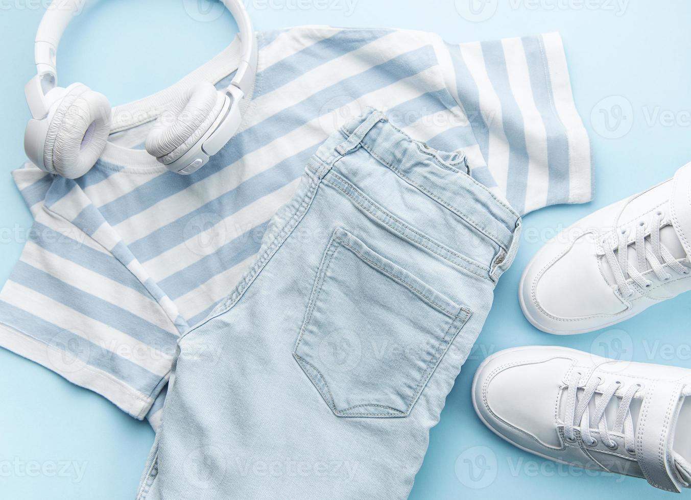 Child's t-shirt, shoes and headphones on blue backgrund photo