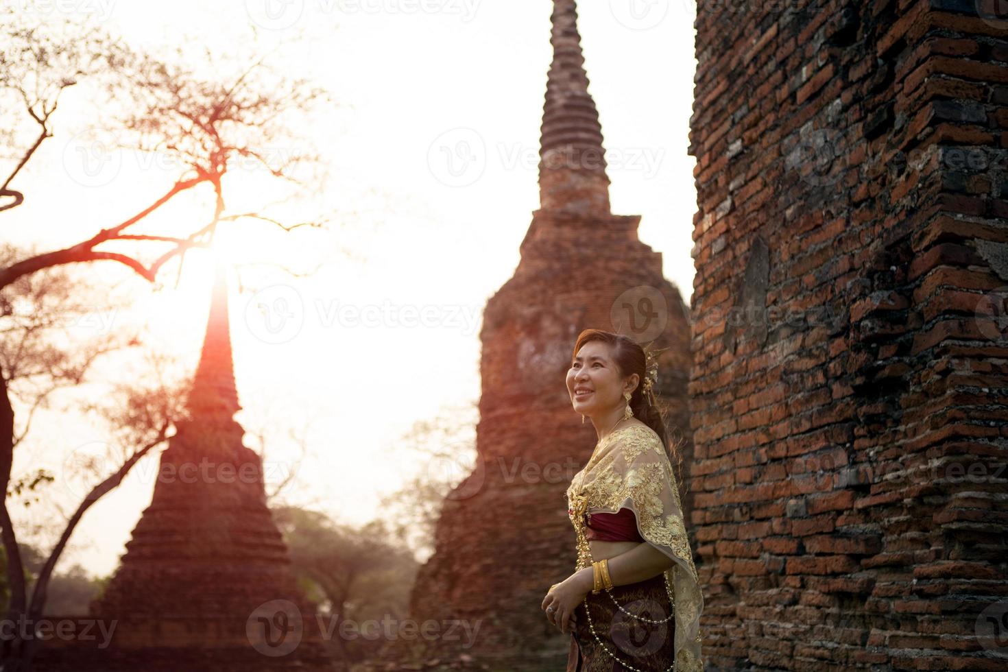 beautiful asian woman wearing thai tradition dress standing against brick wall at old temple of ayutthaya world heritage site of unesco thailand photo