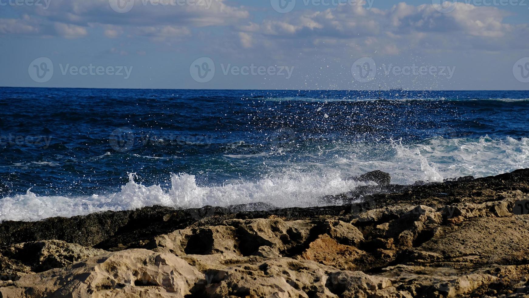 Blue sea wave and white foam and splash. Stone beach on island of Malta, no sandy beach. Summer holiday border frame concept. Tropical island vacation backdrop. Tourist travel banner design template. photo