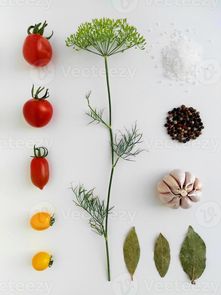 Ingredients for pickling red and yellow tomatoes. Concept culinary recipe preservation of vegetables in harvest season. Assorted tomatoes, garlic, dill, salt, pepper and bay leaf. Knolling concept. photo