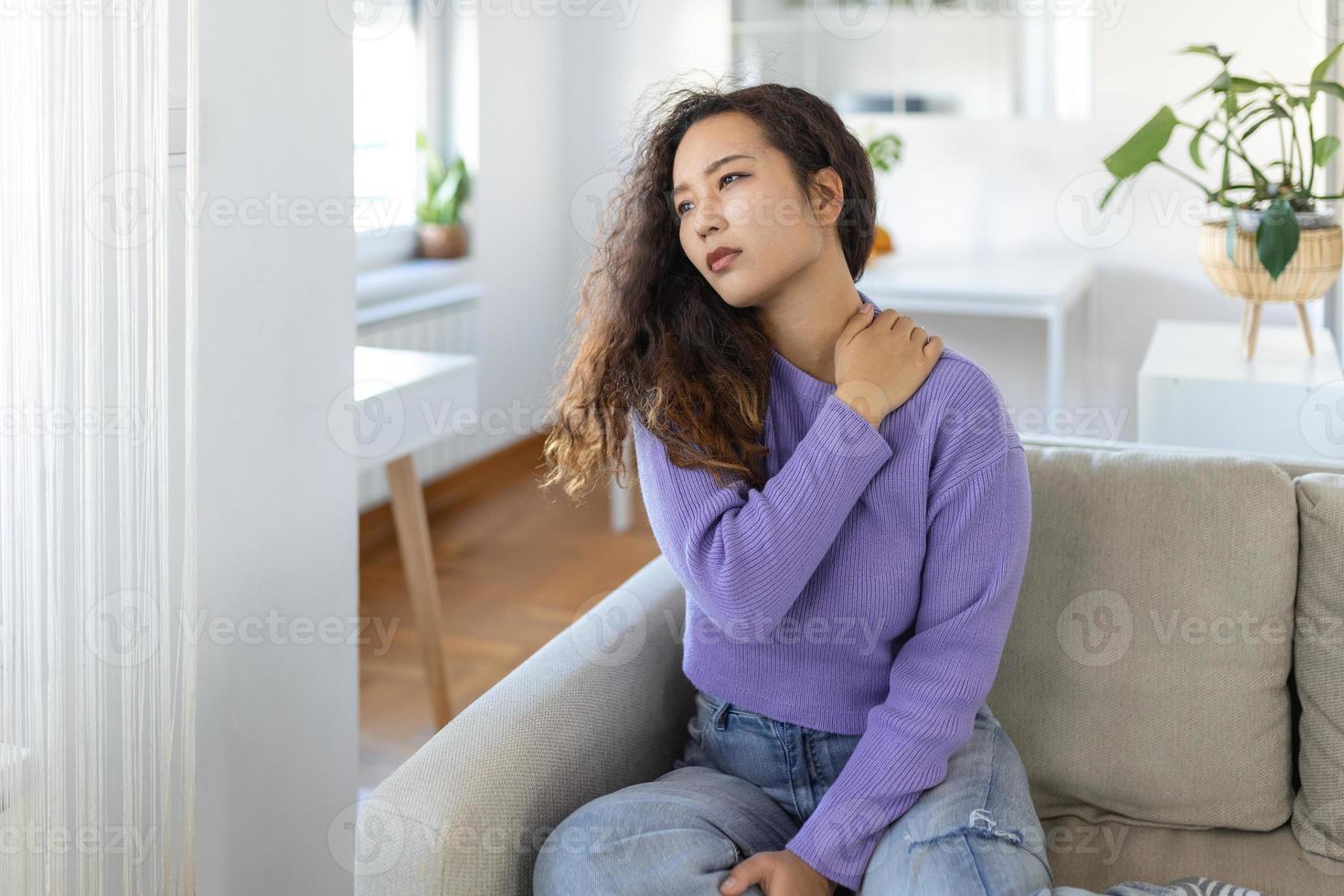 asiático mujer sufrimiento desde dolor de espalda a hogar. inferior espalda dolor . mujer siente espalda dolor masajear dolor músculos, triste mujer sufre desde espalda baja foto